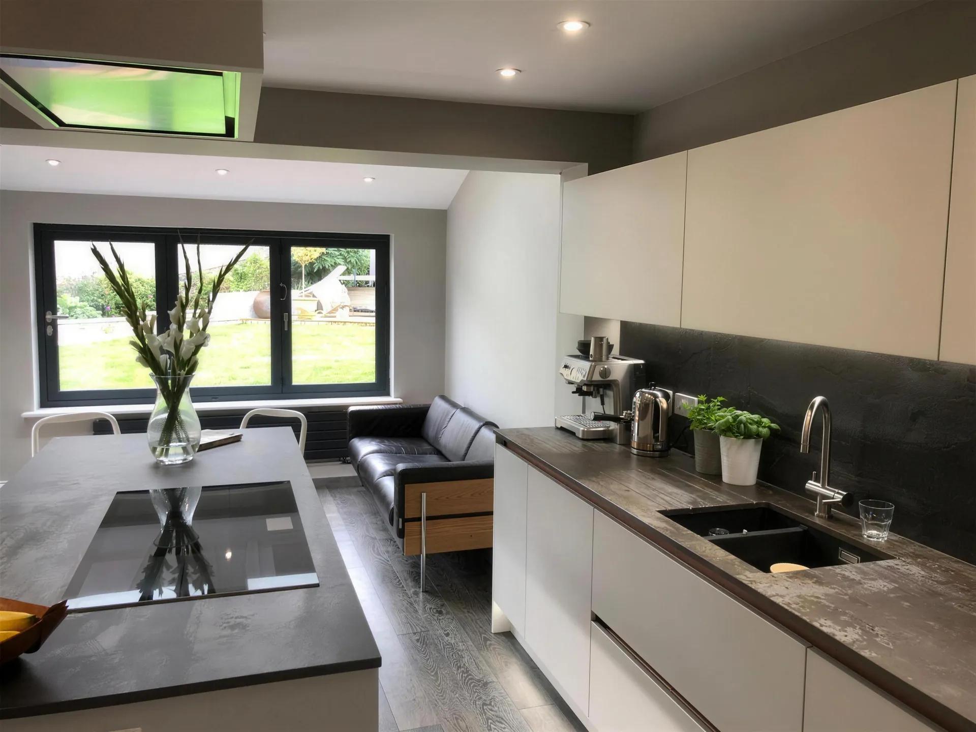 A finished open-plan kitchen extension by A.P. Berrystone, with an island, a roof light and a window onto the garden